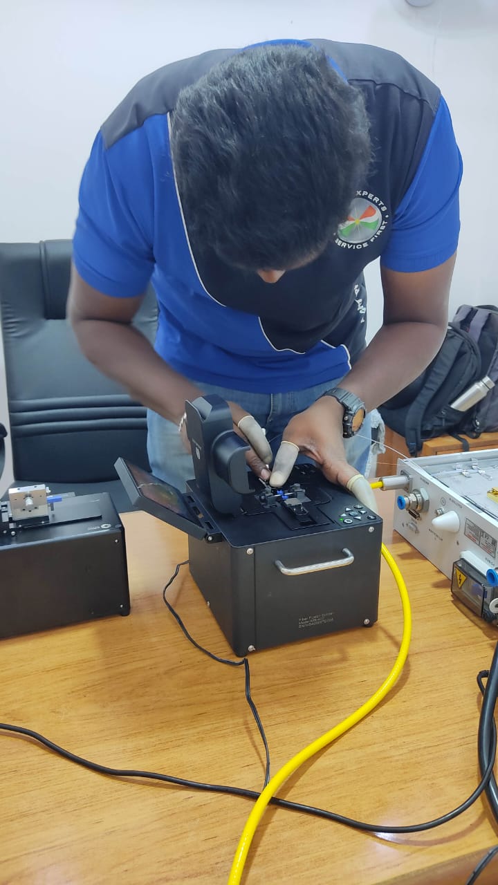 Techniker bedient ein Faserspleißgerät am gelben Lichtleitkabel einer Laserquelle