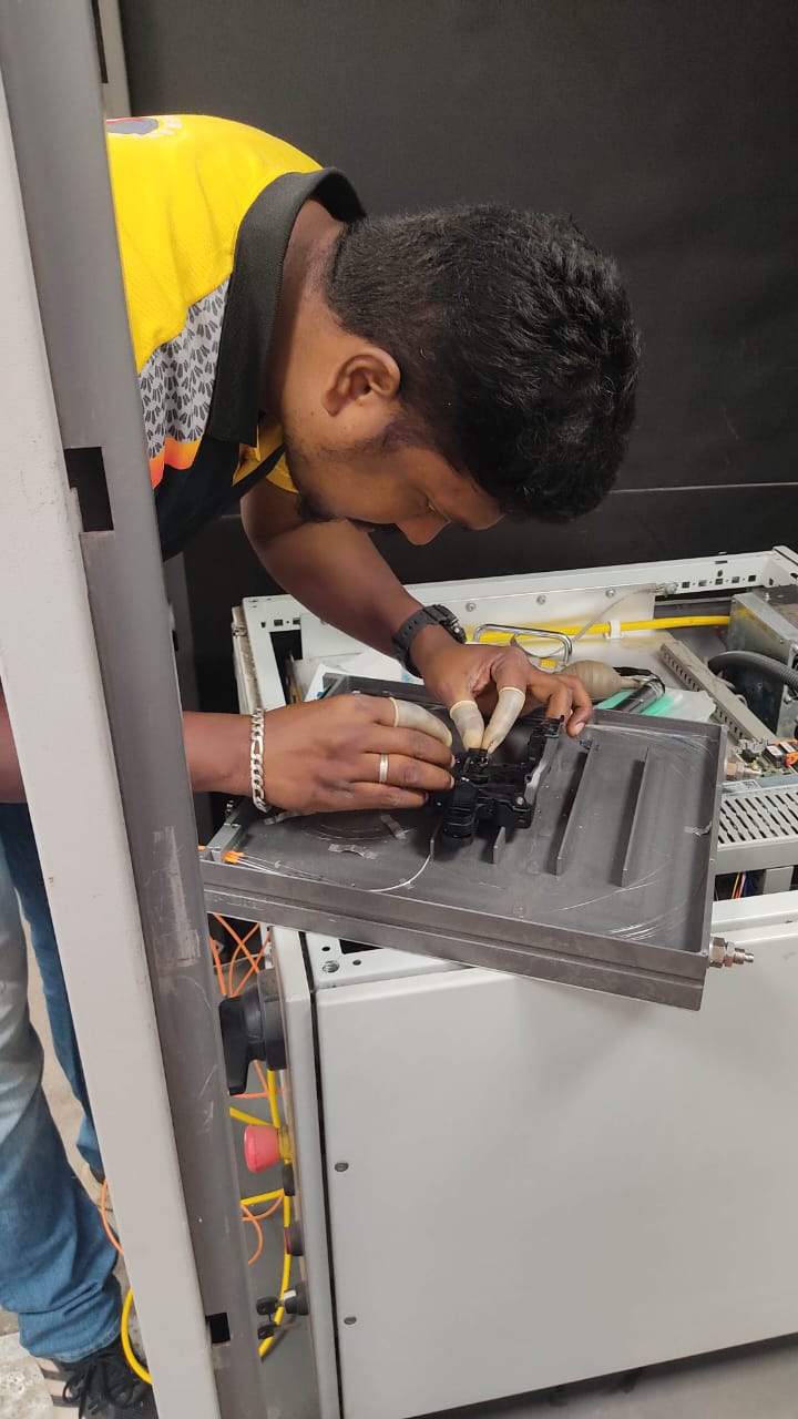 Techniker mit Fingerlingen arbeitet an einer optischen Baugruppe im geöffneten Laserquellenschrank