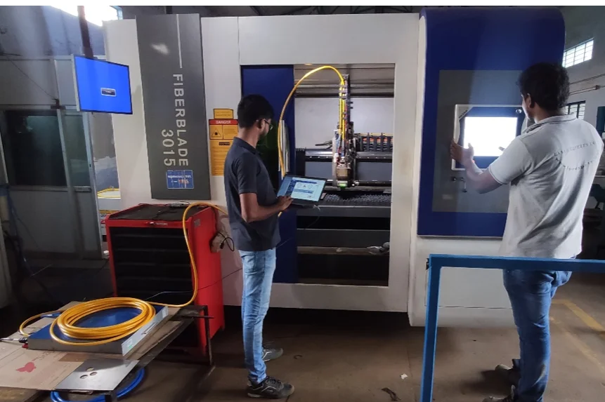Zwei Techniker an einer Faserlaser-Schneidanlage FiberBlade 3015 mit Laptop und Lichtleitkabel